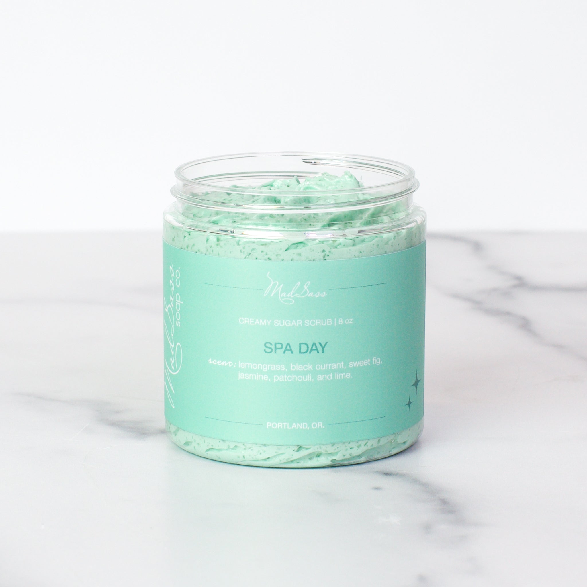 One container of Spa Day Creamy Sugar Scrubs on a white background. Spa Day is a light teal scrub in a clear tub.