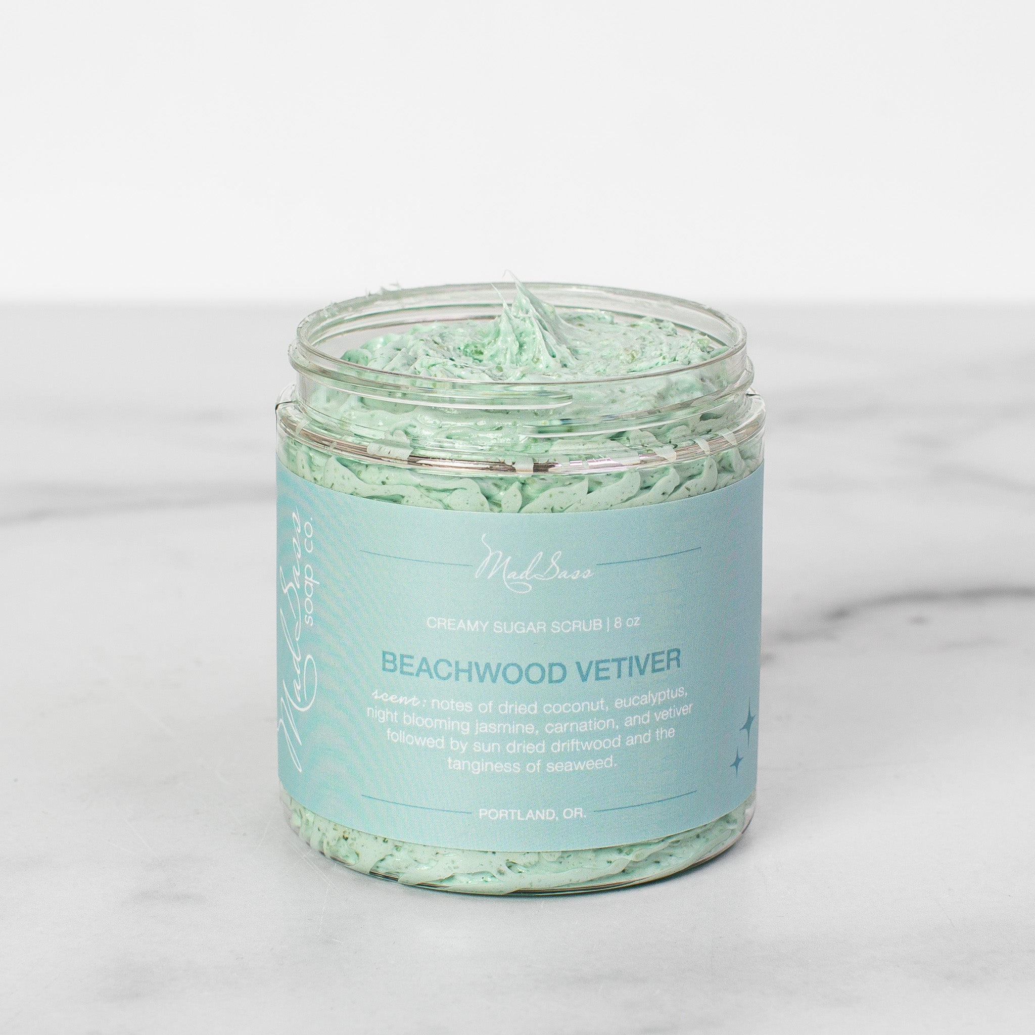 One container of Beachwood Vetiver Creamy Sugar Scrubs on a white background. Beachwood Vetiver is a light blue scrub in a clear tub.