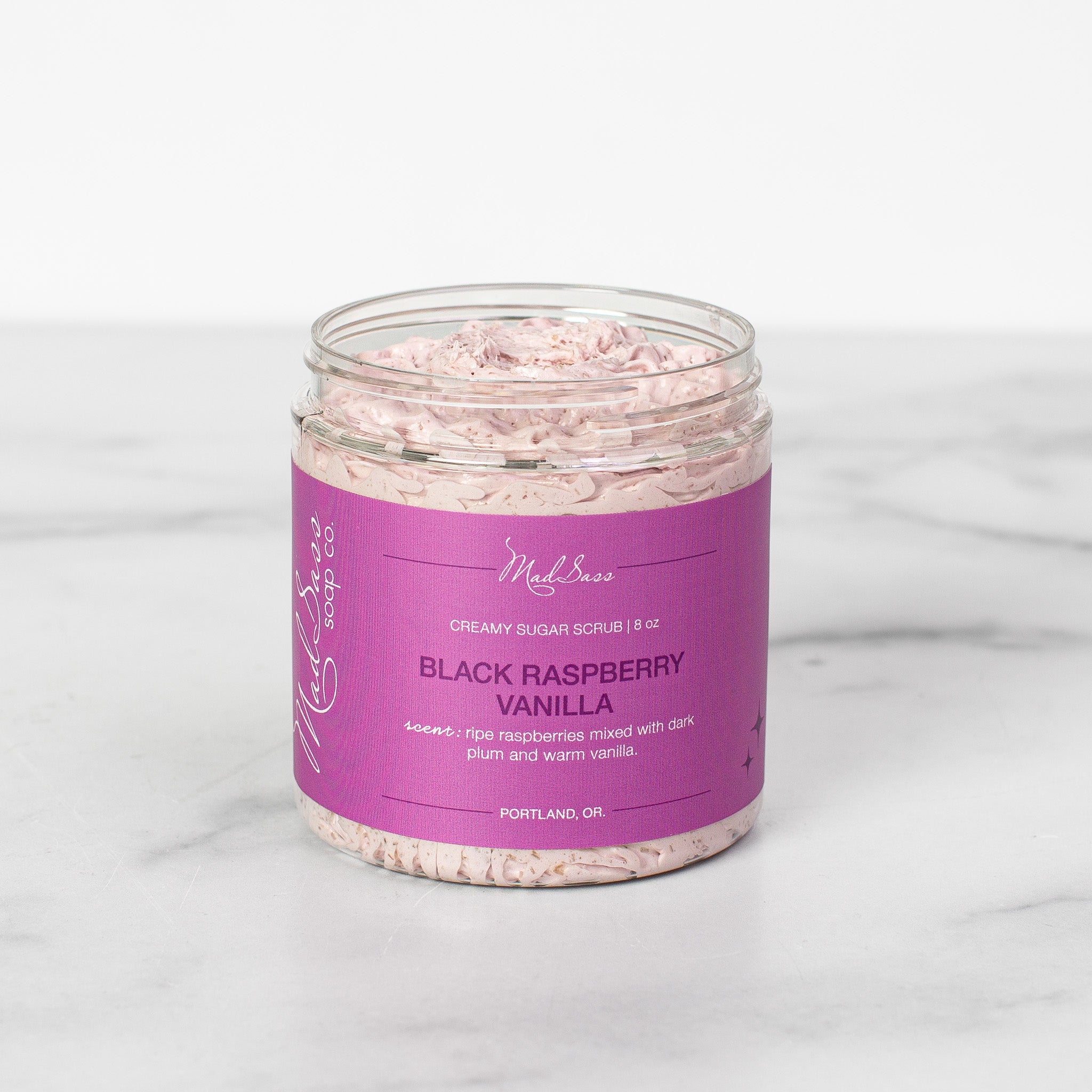 One container of Black Raspberry Vanilla Creamy Sugar Scrubs on a white background. Black Raspberry Vanilla is a light purple scrub in a clear tub.