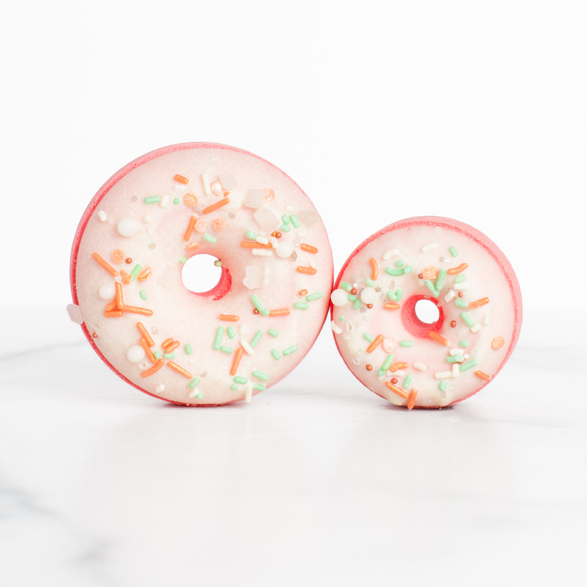 Two luxurious Peach Blossom bath bombs by Mad Sass Soap Co, showcasing a donut design in pink with colorful sprinkles, perfect for a hydrating luxury bath experience.