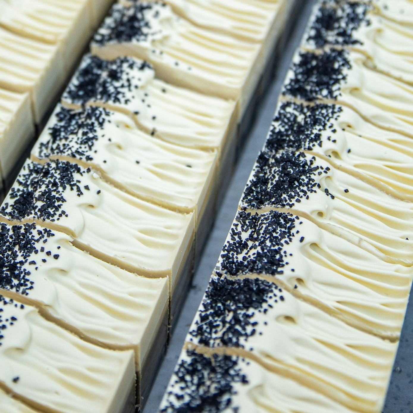 Areal view of two rows of Birchwood Oud soap. Soap is topped with black sea salt on the left edge.