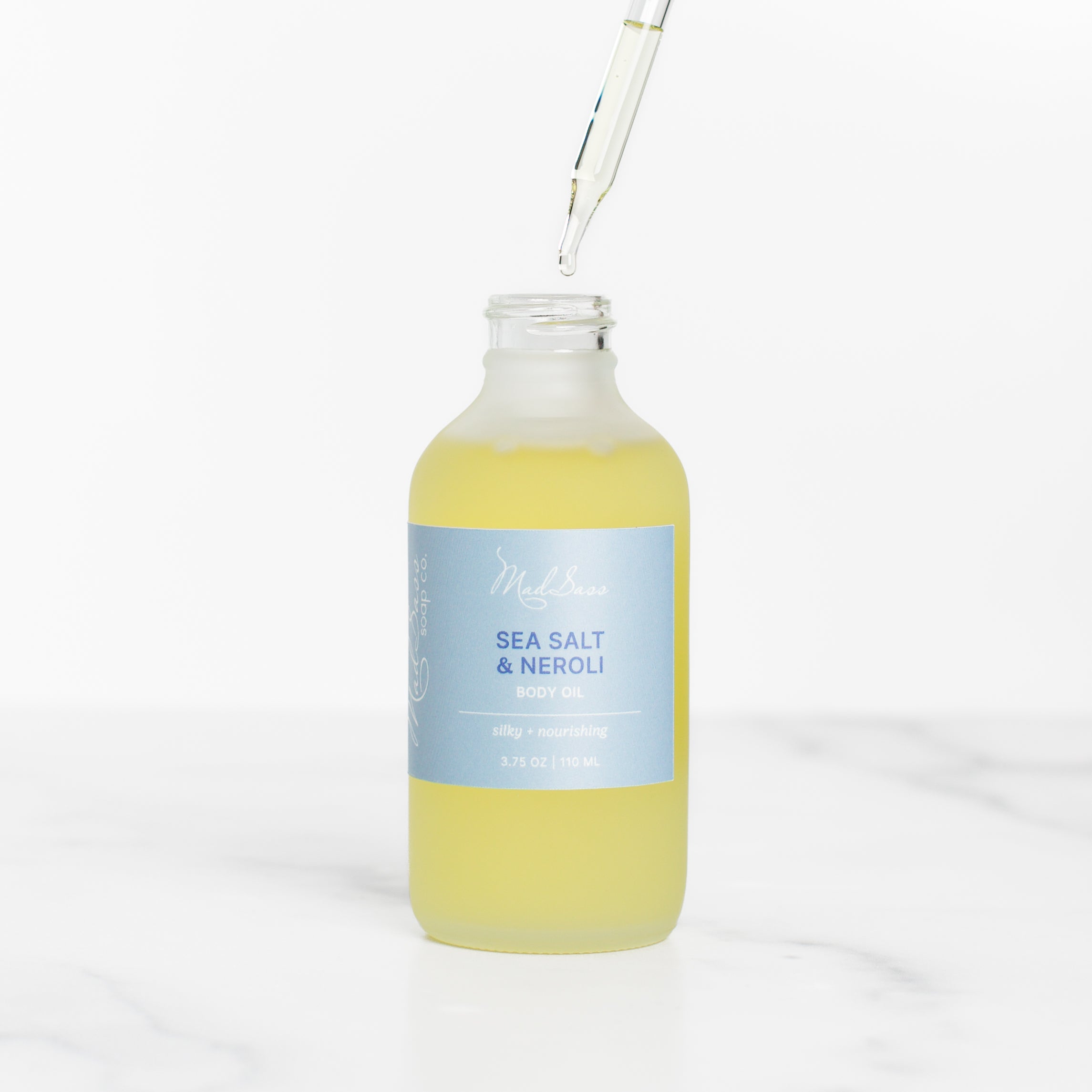 Close-up of Sea Salt & Neroli - Body Oil by Mad Sass Soap Co with a dropper, highlighting the golden liquid, ideal for skin nourishing body oil, ensuring a silky and radiant finish.