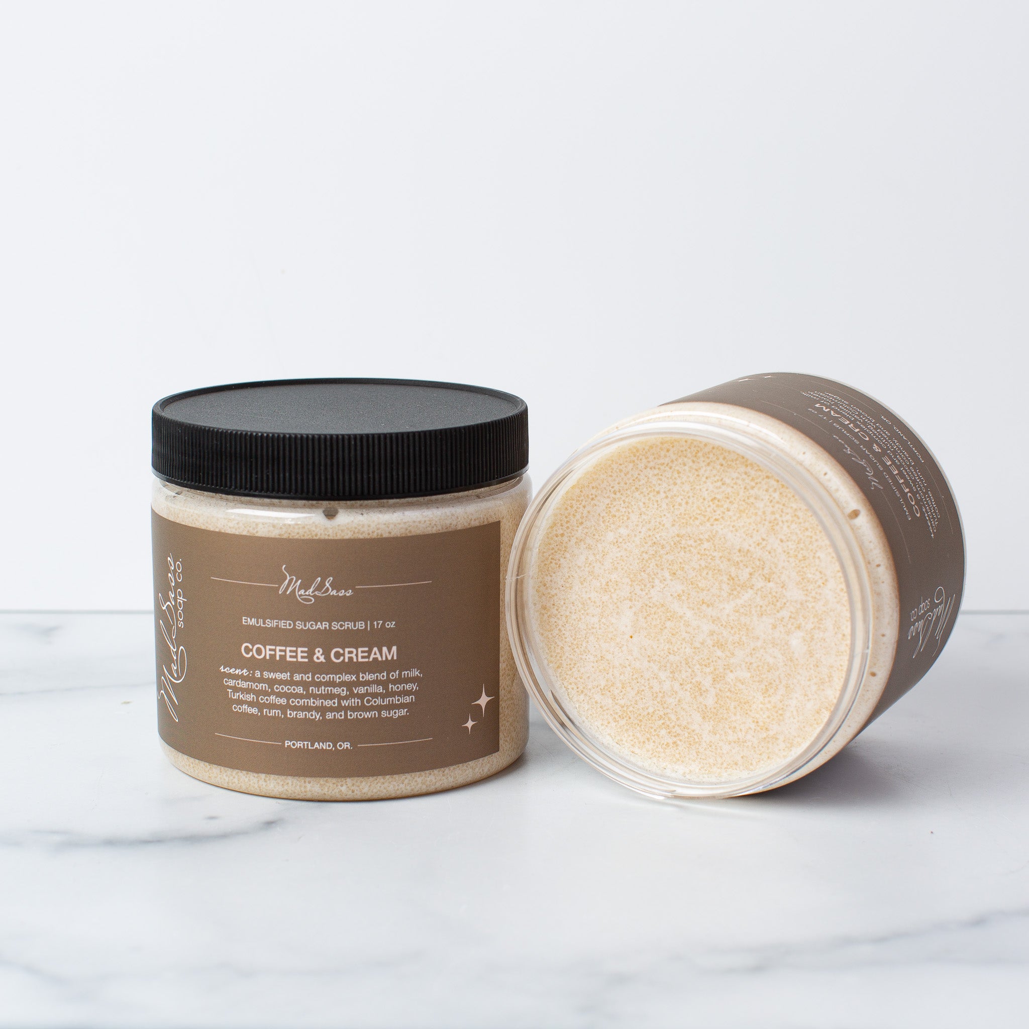 Two Coffee & Cream Emulsified Sugar Scrubs, with one on its side, on a white background.