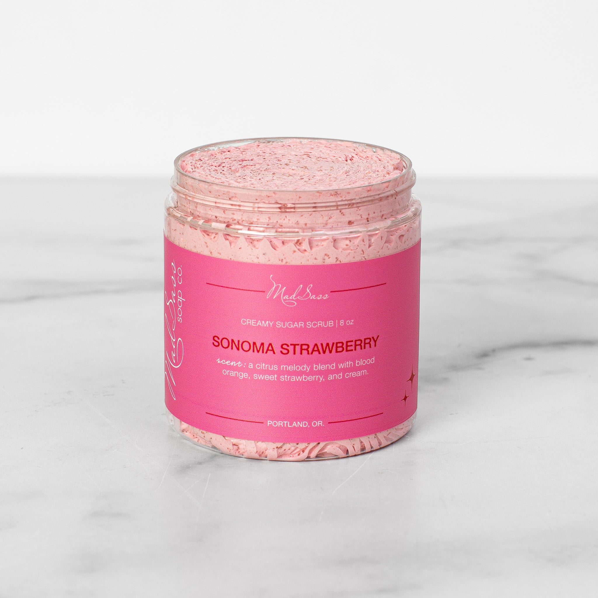 One container of Sonoma Strawberry Creamy Sugar Scrubs on a white background. Sonoma Strawberry is a light pink scrub in a clear tub.