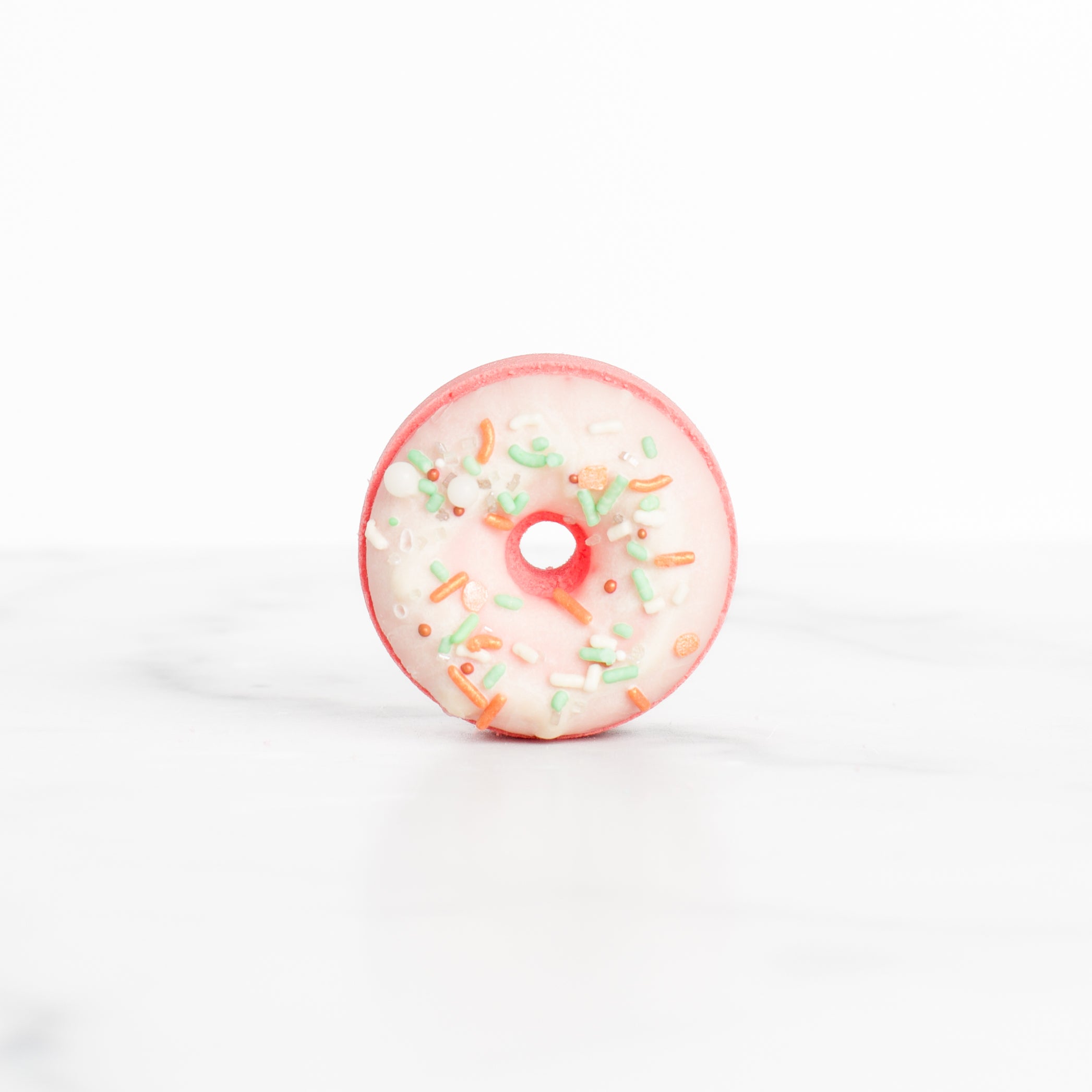 A single Peach Blossom bath bomb by Mad Sass Soap Co, designed as a pink donut with sprinkles, embodying the essence of a hydrating luxury bath bomb.