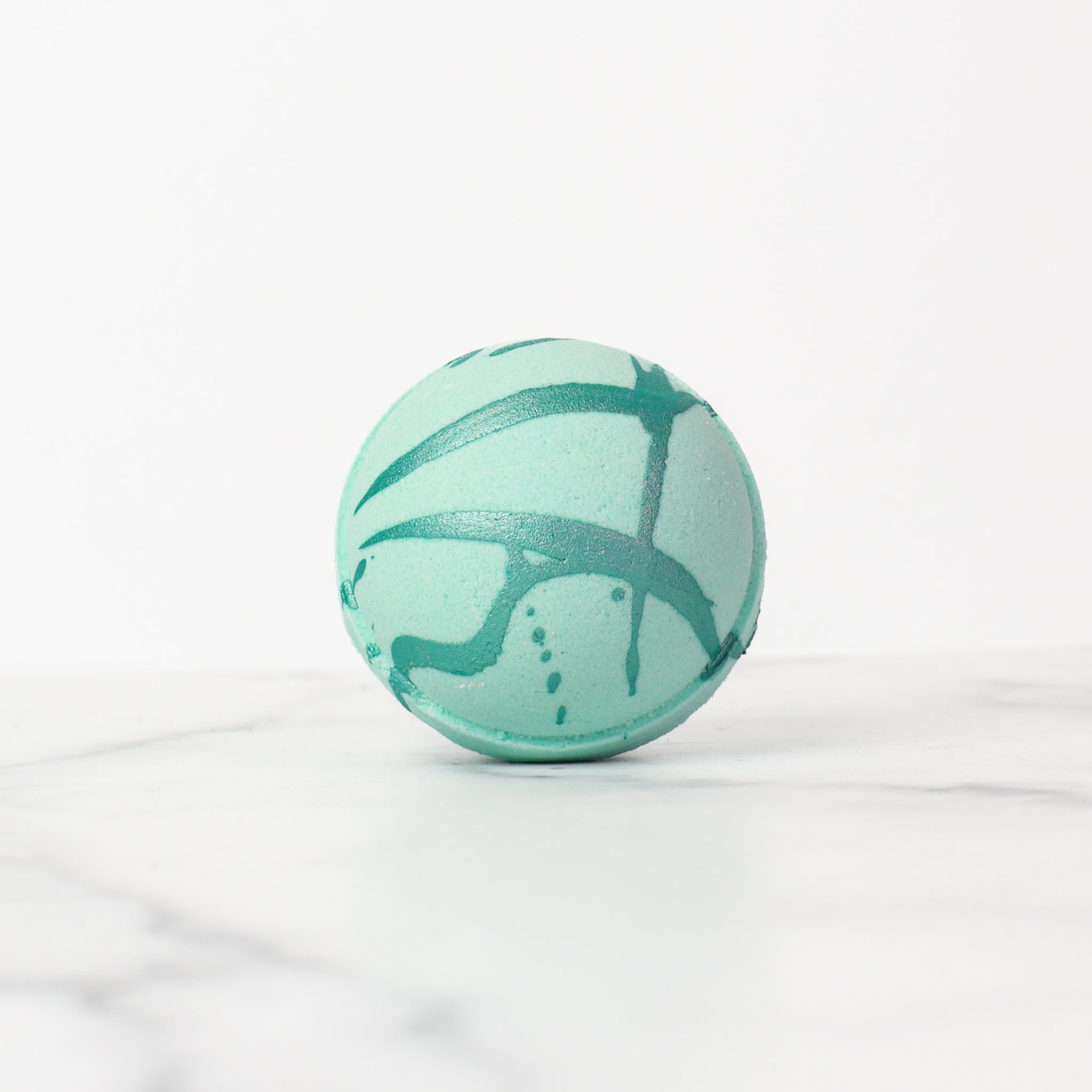 Close-up of a Spa Day bath bomb by Mad Sass Soap Co, showcasing its exquisite texture and elegant teal pattern, ideal for transforming your bathtub into a serene spa.