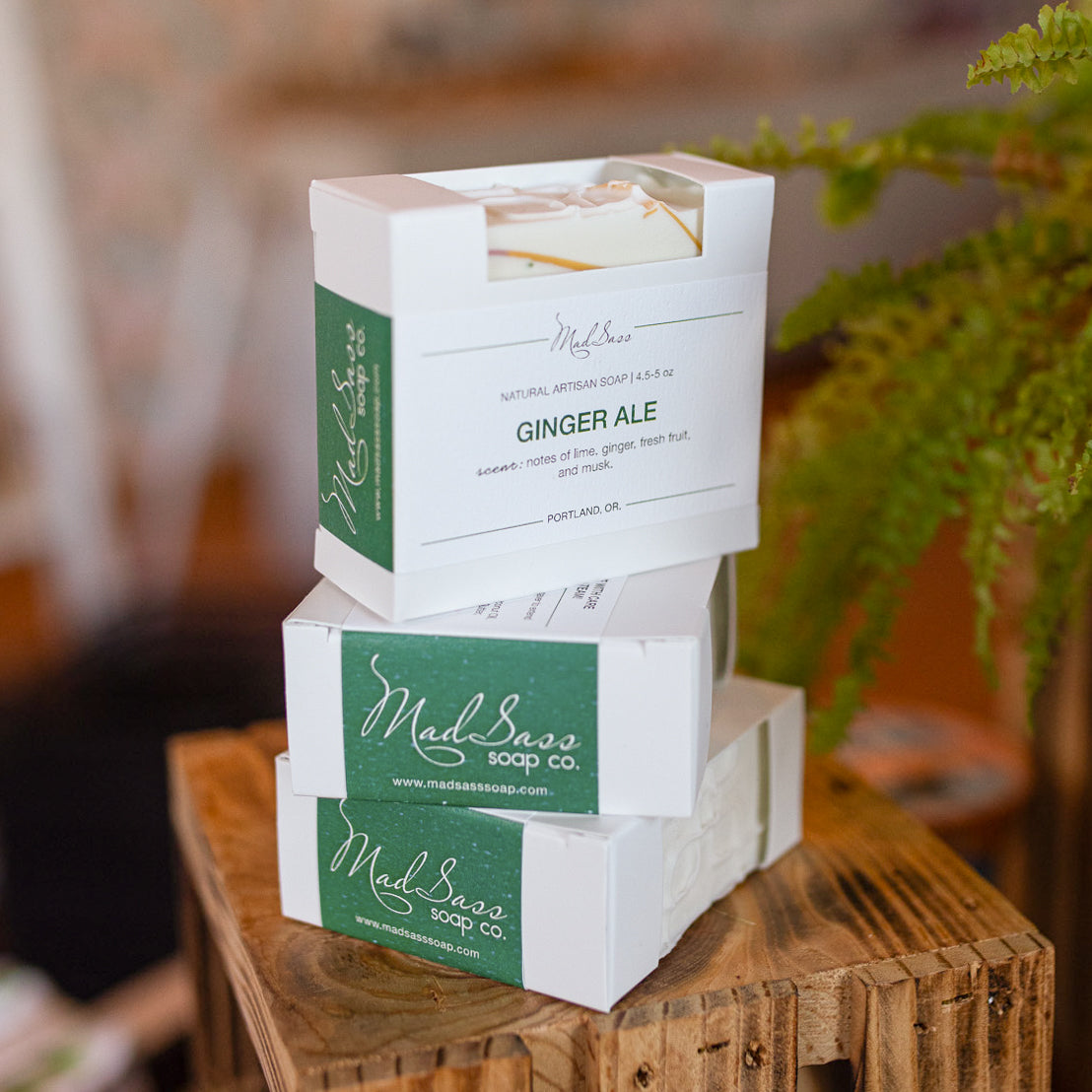 Three boxes of Ginger Ale soap stack on each other on a wooden block.