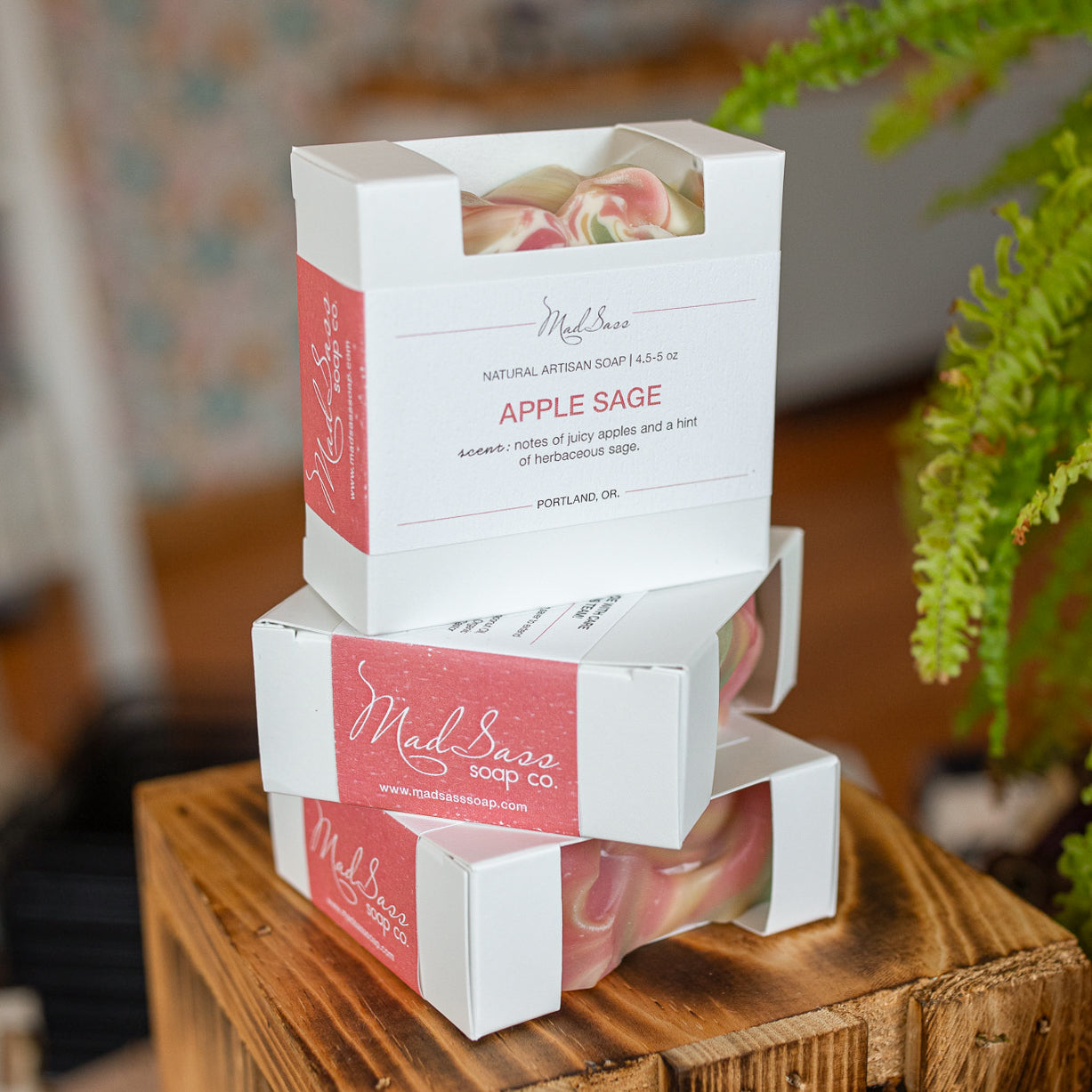 Three boxes of Apple Sage soap stacked on top of each other on a wooden block.
